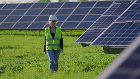 Industrial Woman Engineer in Uniform Walking Through Solar Panel Field for Examination