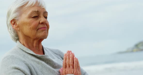 Senior woman meditating on beach