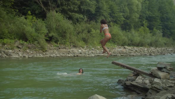 Carefree Diverse Multicultural People Diving Into Mountain River Off Springboard