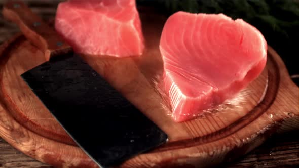 Super Slow Motion Raw Tuna Steak Drops a Cutting Board with Splashes of Water