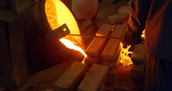 Male worker pouring molten metal in mold at workshop 4k