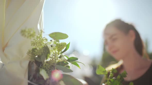 Browhaired Female Decorating Wedding Arch with Flowers in Slowmotion