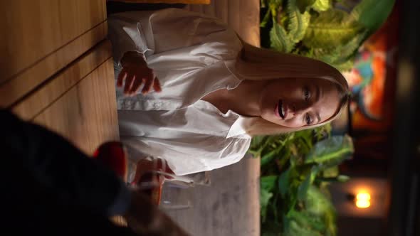 Vertical Shot of Attractive Young Blond Woman Sitting Inside Cozy Restaurant Talking Smiling