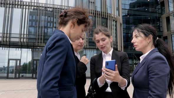 Group of Female Coworkers Seriously Discuss What They See in a Smartphone