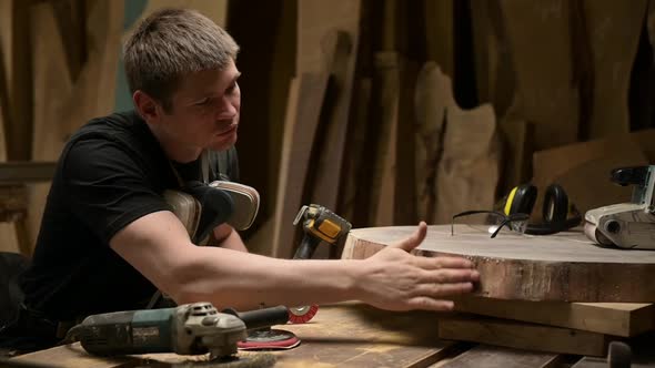 The carpenter blows and shakes off dust from the treated wood surface.