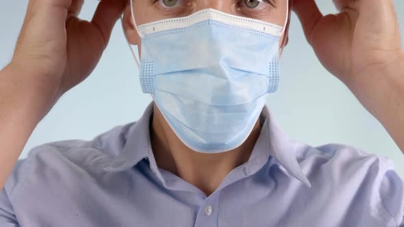 Extreme Closeup of Man Putting Disposable Face Mask Over Mouth and Nose