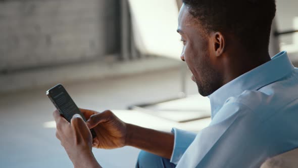 Young african american student taking notes using smartphone