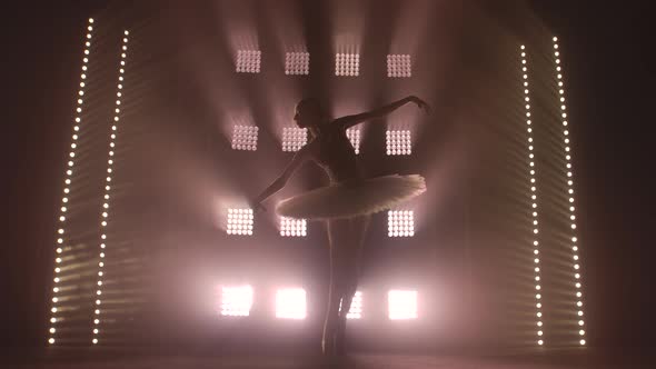 Graceful Hard-working Ballerina Dancing in White Dress in the Studio in Spotlight on a Black