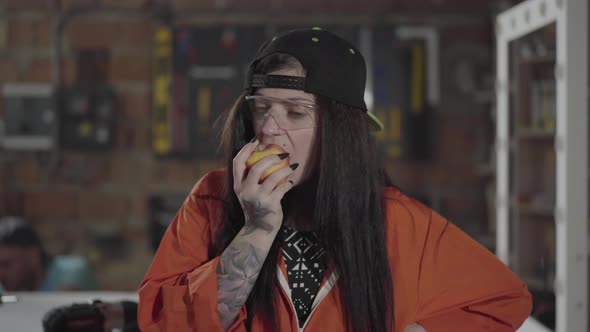 Confident Female Worker Eating the Apple in the Foreground Close Up