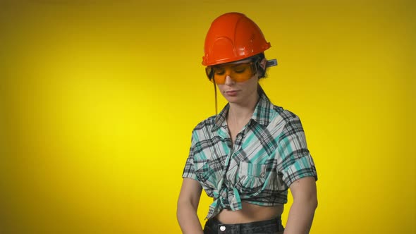 Girl Engineer Builder in an Orange Safety Helmet Holds a Level Ruler in Hands