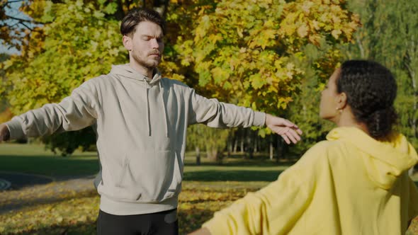 Man and Woman Doing Breathing Exercises at the Park in the Autumn Morning