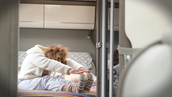 Adult woman doing sport healthy exercise inside camper van bedroom. Health and good lifestyle female