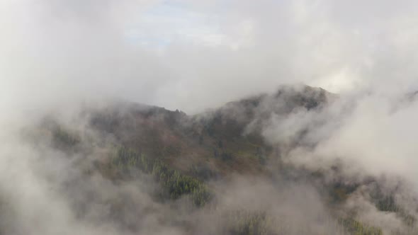 drone flight over autumn mountain in foggy clouds