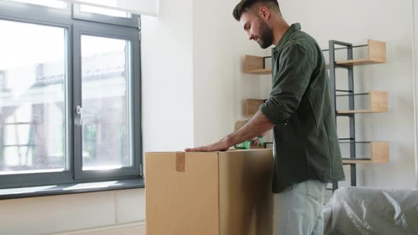 Man with Adhesive Tape Gun Packing Box at Home