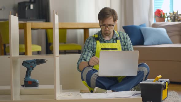 Furniture Assembly Worker Using Laptop To Consult Instructions at Customer Home