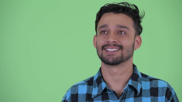 Face of Happy Young Bearded Persian Hipster Man Thinking