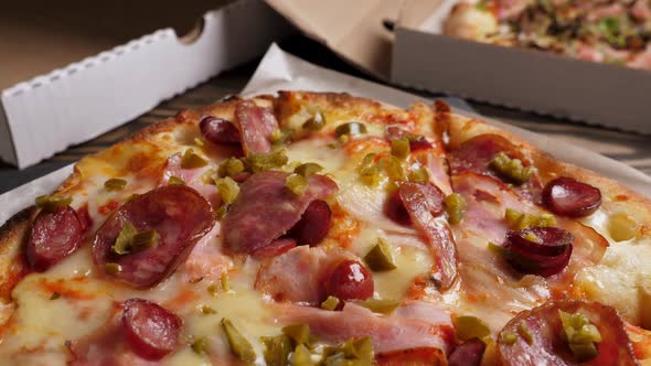 One Salami and Bacon Pizza Rotating on Boxes with Pizza Background