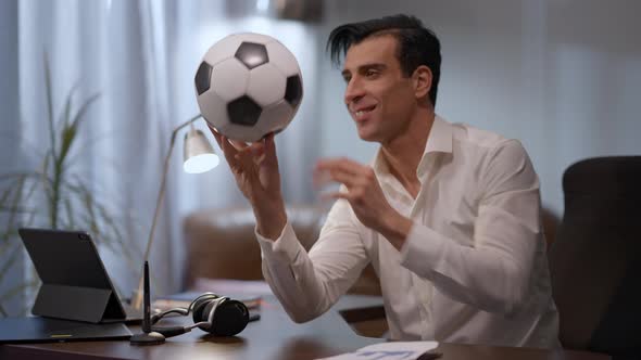 Joyful Young Middle Eastern Man Spinning Ball Smiling Sitting at Table in Home Office