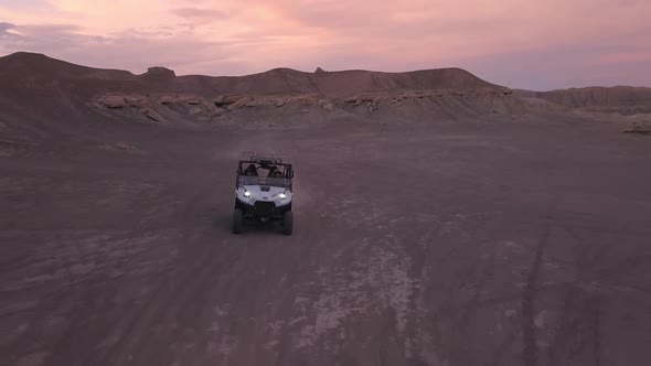 OHV driving over hill in the desert while flying backwards