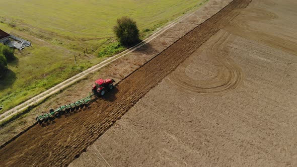 A Farmer on a Tractor Uses a Harrow Seeder, Cultivates the Soil, Prepares the Fields for Sowing