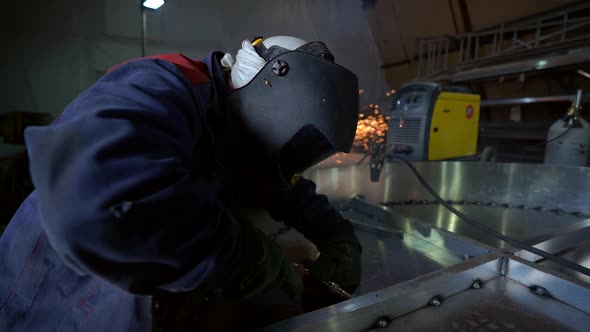 Welder Is Working with Metal Details at Workshop of Plant, Wearing Mask