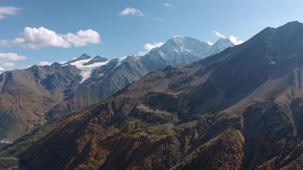 Sunny Highland with Rocky Slopes Cheget Mountain and Snowy Peaks Aerial View