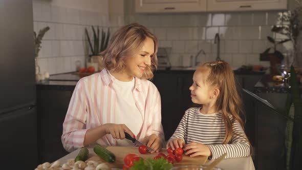 Cute Mom Teaches Her Little Daughter How To Make Fresh Vegetable Salad in Her Kitchen at Home