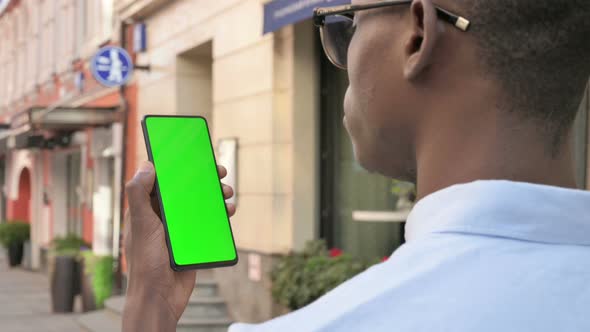 Rear View of African Man Looking at Smartphone with Green Chroma Screen