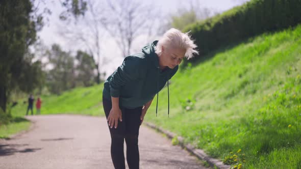 Wide Shot of Greyhaired Gorgeous Fit Senior Woman Bending in Slow Motion Training Outdoors in