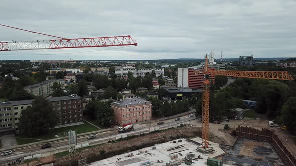 drone shot of cranes on construction site and traffic red bus