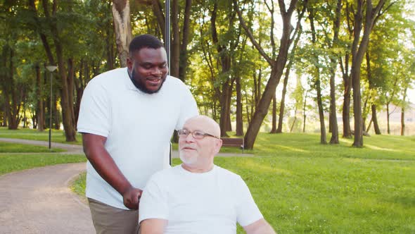 African-American caregiver and old disabled man in a wheelchair. Nurse and patient.