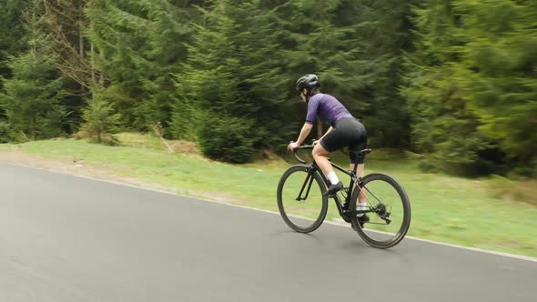 Cyclist on bicycle. Professional female cyclist riding bike out of saddle in mountains.