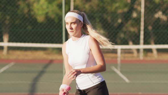 Video of focused caucasian female tennis player holding racket and hitting ball
