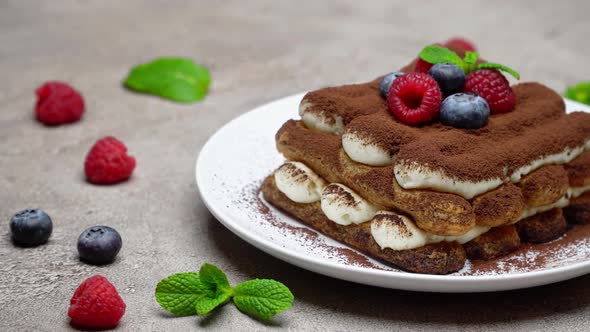 Portion of Classic Tiramisu Dessert with Raspberries and Blueberries on Grey Concrete Background