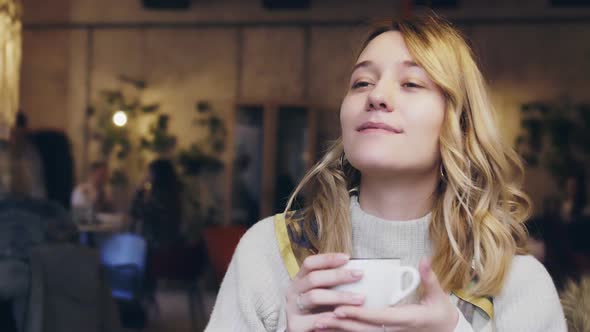 Young and Beautiful Girl Sitting in Cafe and Drinking Coffe Blogger