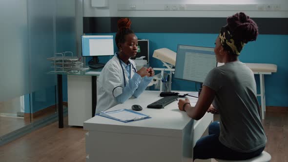 Woman Working As Doctor Talking to Patient About Sickness