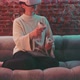 Young woman siting on the couch wearing vr goggles and husing handles to experience vr - VideoHive Item for Sale