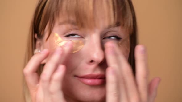 Beautiful Smiling Woman with Short Hair in Gold Eye Patches Looking in Camera and Smiling Over