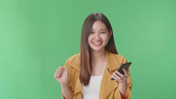 Asian Woman Surprise And Say Wow During Use Mobile Phone While Standing On Green Screen Studio