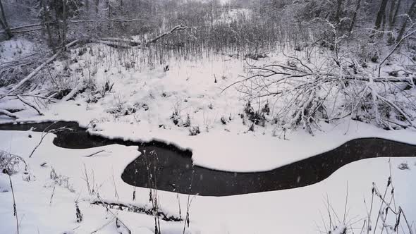 Heavy snowfall on remote stream in arctic forest, winter landscape
