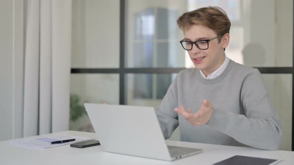 Young Man Talking on Video Chaton Laptop in Modern Office