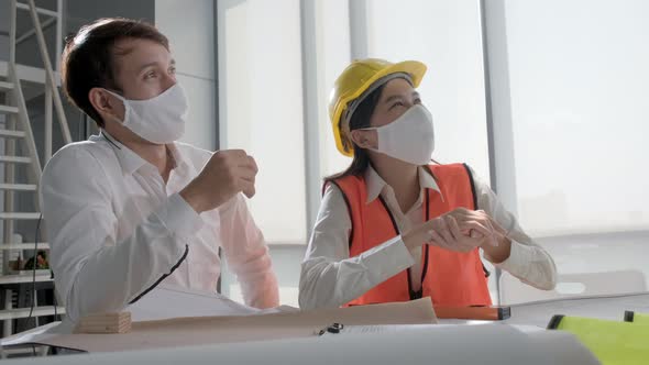 engineer caucasian male and asian female serious concentrate meeting with mask protection