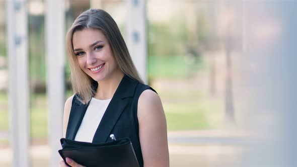 Portrait of Beautiful European Businesswoman Smiling and Taking Off Glasses Standing Outdoor