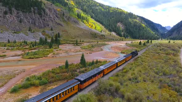 Aerial Fly Along of Locomotive Train in Mountain Valley By Stream Leaving Silverton for Durango in