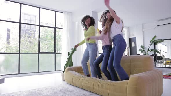 Three United Young Women Having Fun Dancing on the Sofa While Listening Music