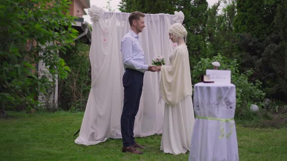 Wide Shot of Happy Loving Bride and Groom Standing at Altar Outdoors Holding Hands Talking