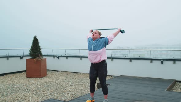 Sporty Girl in Sportswear Does Yoga Stretching Exercising Using Rubber Band on Roof of House Outdoor