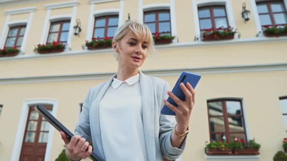 A Bottom View at Attractive Businesswoman Looking at Smartphone Outdoors