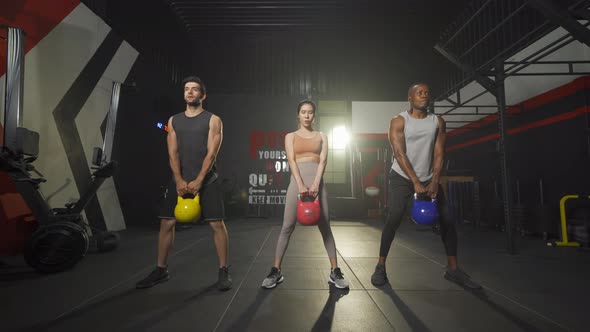 Group of multi ethnic people holding weight kettle bell twist, cardio. Strength training workout