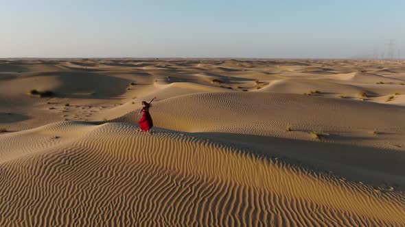 Athletic Woman in Long Red Dress is Dancing in the Sands of Rub Al Khali